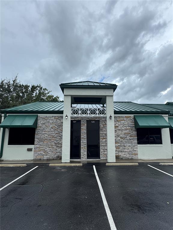 A single-story commercial building with a stone facade, green metal roof, and two glass entrances — 129 E 13TH STREET UNIT B, ST CLOUD, FL