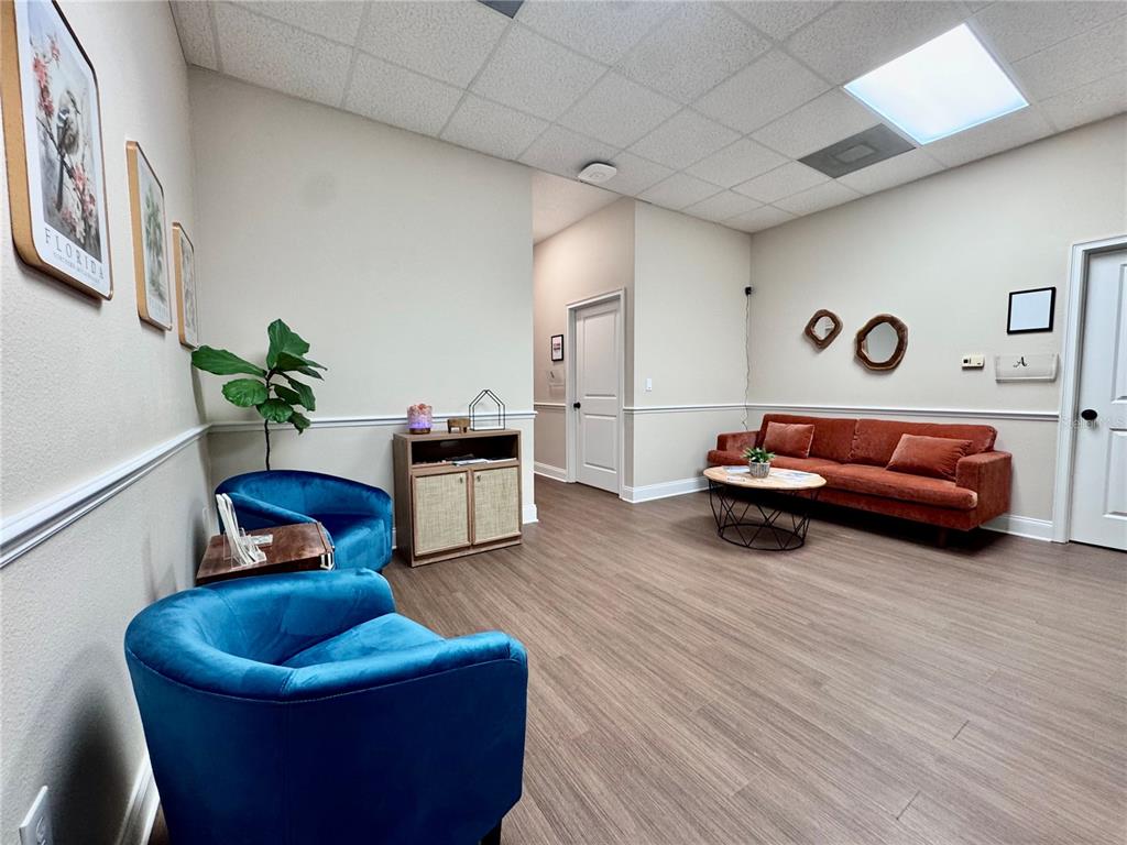 A waiting room features blue velvet chairs, an orange sofa, and wood-look flooring — 129 E 13TH STREET UNIT B, ST CLOUD, FL