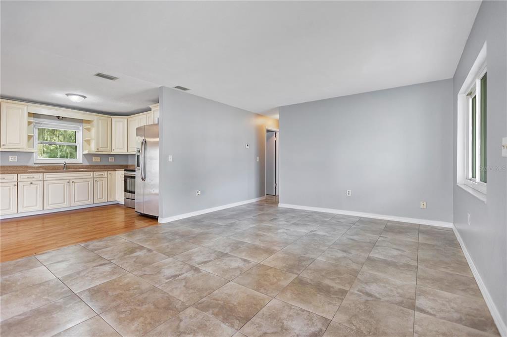 An empty room features light blue walls, large square floor tiles, and a wide window — 8316 TUPELO DR, TEMPLE TERRACE, FL