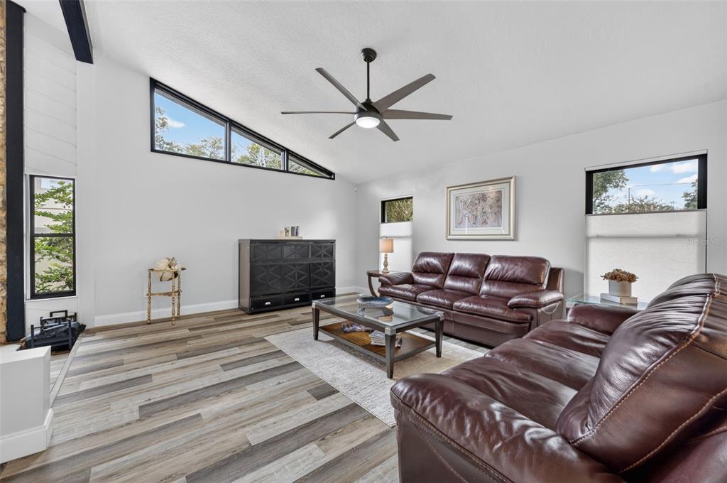 A living room with vaulted ceilings, dark leather sofas, and wood-look flooring — 6601 BRENDA DRIVE, APOPKA, FL