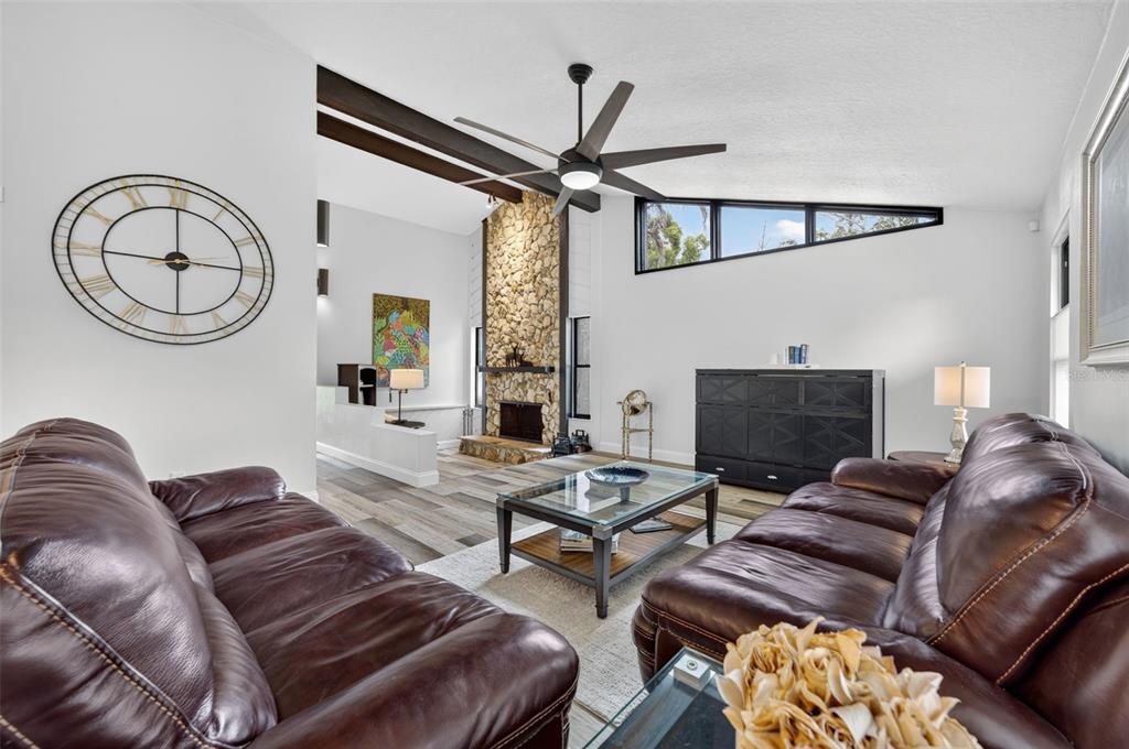 A living room features a stone fireplace, vaulted ceilings with exposed beams, and brown leather sofas — 6601 BRENDA DRIVE, APOPKA, FL