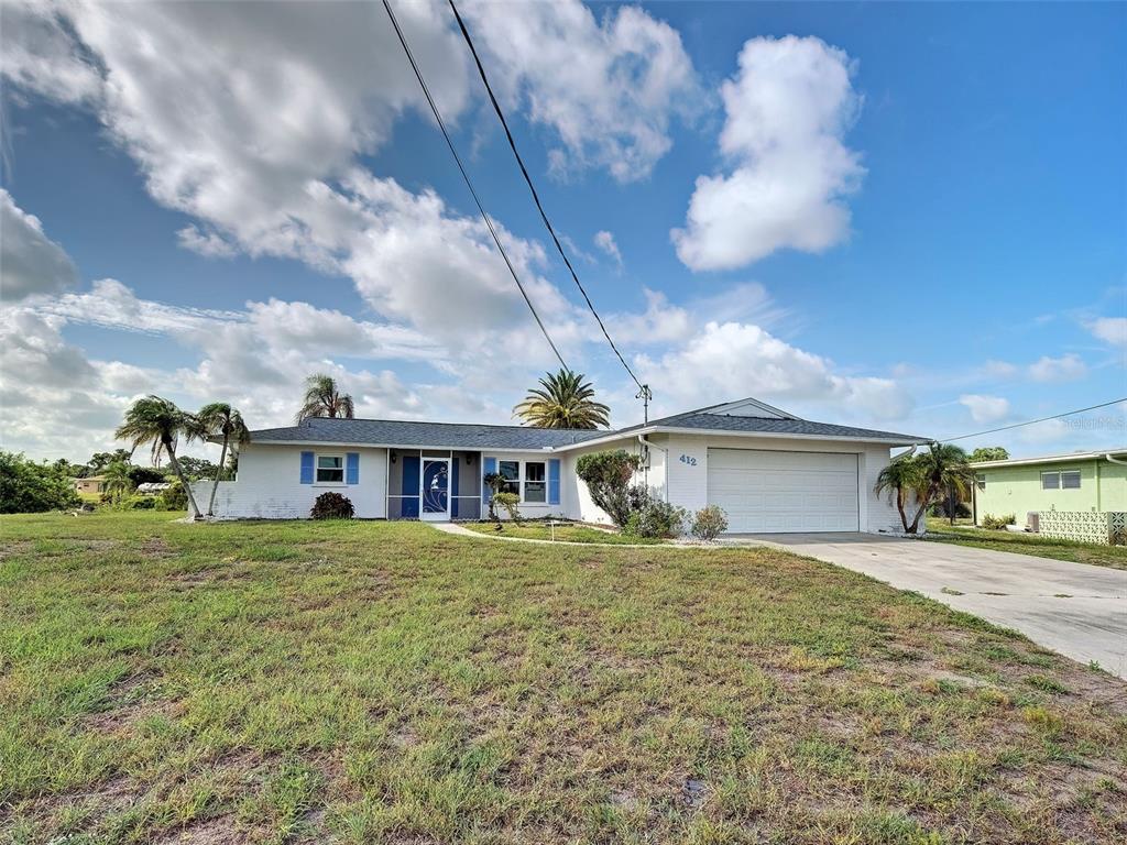 A white single-story house with a garage and palm trees under a blue sky — 412 PINE TREE TERRACE, VENICE, FL