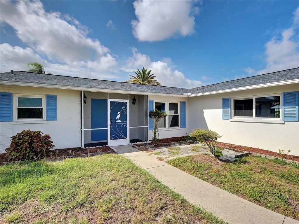 A single-story house with a white exterior, blue shutters, and a screened-in front entryway — 412 PINE TREE TERRACE, VENICE, FL