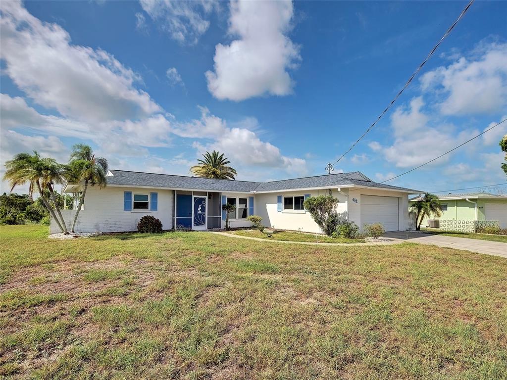 A single-story white house with blue shutters, a garage, and palm trees under a blue sky — 412 PINE TREE TERRACE, VENICE, FL
