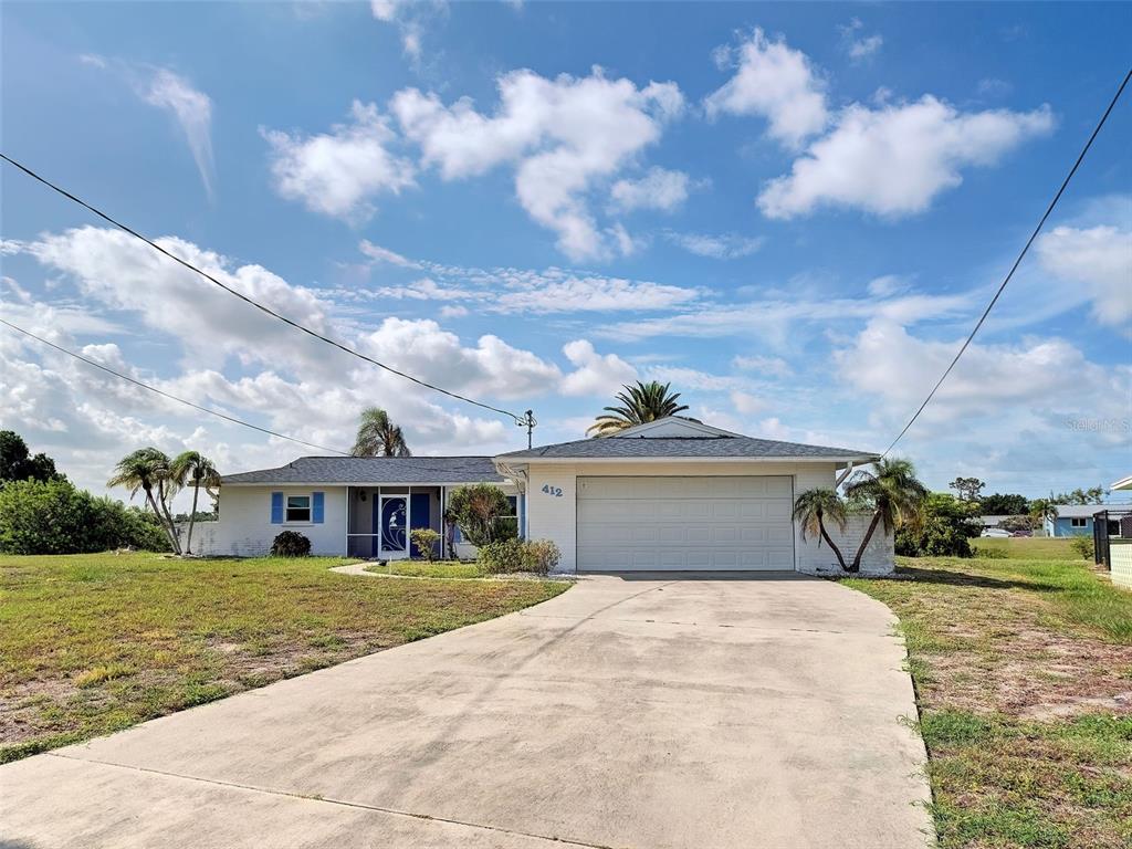 A single-story white house with a two-car garage and a concrete driveway under a blue sky — 412 PINE TREE TERRACE, VENICE, FL