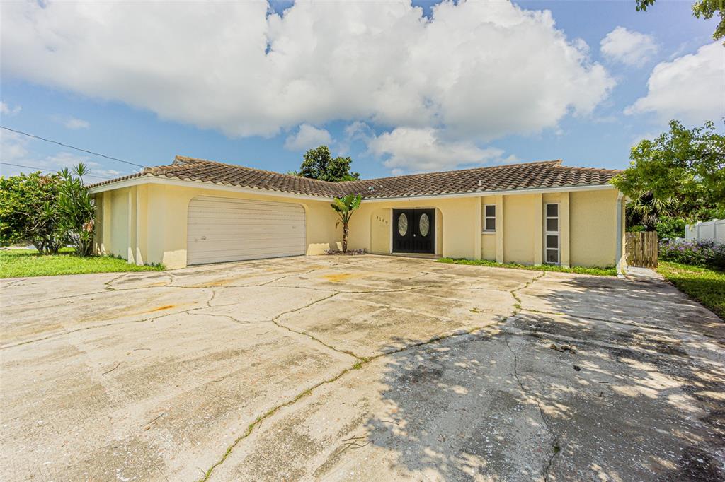 A single-story house with a tiled roof, a large cracked concrete driveway, and double doors — 4149 FLORAMAR TERRACE, NEW PORT RICHEY, FL