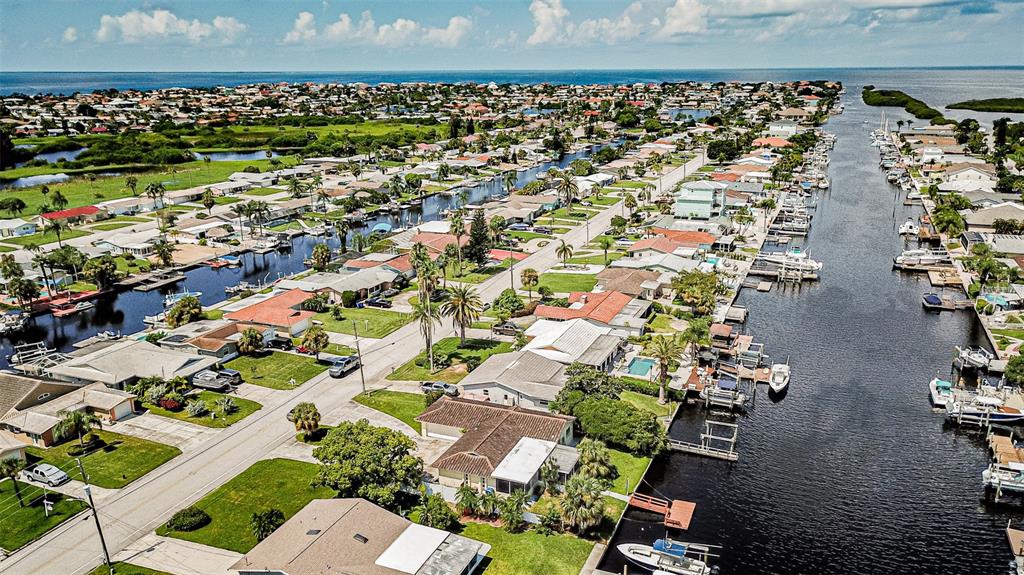 An aerial view of a coastal neighborhood featuring houses, canals, and docked boats — 4149 FLORAMAR TERRACE, NEW PORT RICHEY, FL
