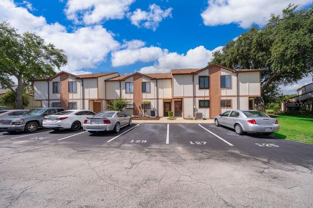A two-story apartment building exterior with a parking lot in the foreground — 129 WHITE FAWN DRIVE UNIT 1290, DAYTONA BEACH, FL