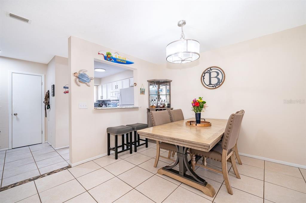 A dining area features a wooden table, upholstered chairs, a corner cabinet, and tile flooring — 129 WHITE FAWN DRIVE UNIT 1290, DAYTONA BEACH, FL