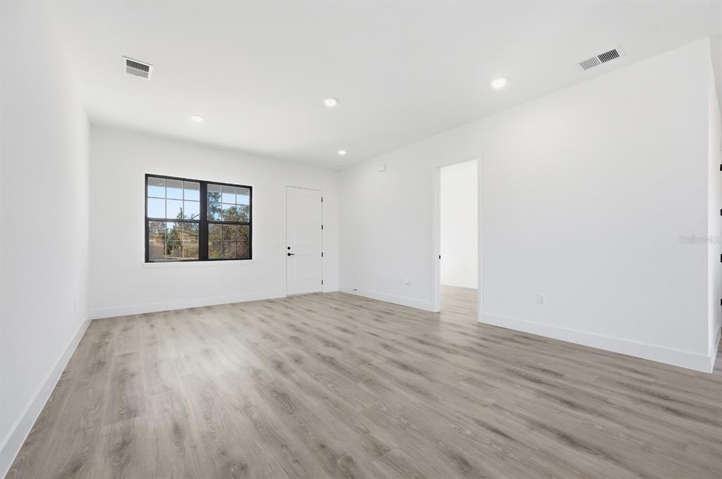 An empty room with white walls, light wood-look flooring, recessed lighting, and a window — 15085 SW 50TH AVENUE ROAD, OCALA, FL