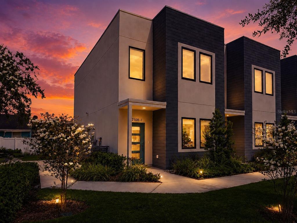 A modern two-story duplex with dark siding and light stucco exterior at sunset — 2108 E 22ND AVENUE UNIT 1, TAMPA, FL