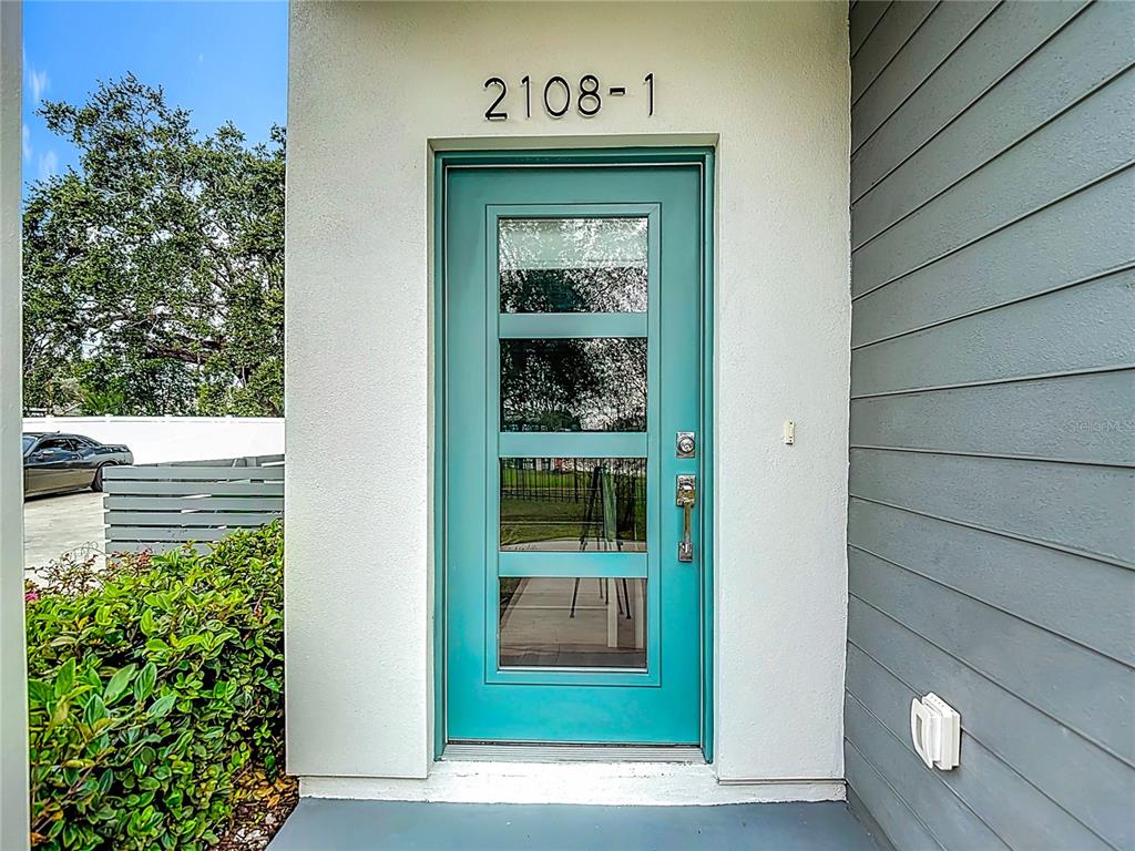 A teal front door with four glass panels is set in a white exterior wall — 2108 E 22ND AVENUE UNIT 1, TAMPA, FL