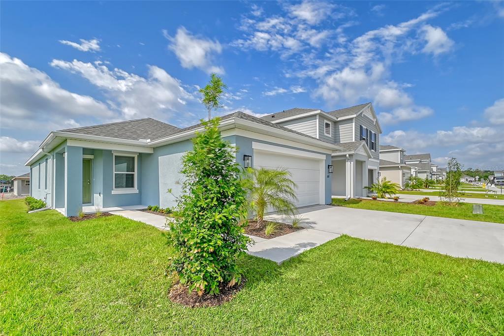 A light blue single-story house with a two-car garage and a small front yard — 13028 SASSAFRAS TRAIL, PARRISH, FL