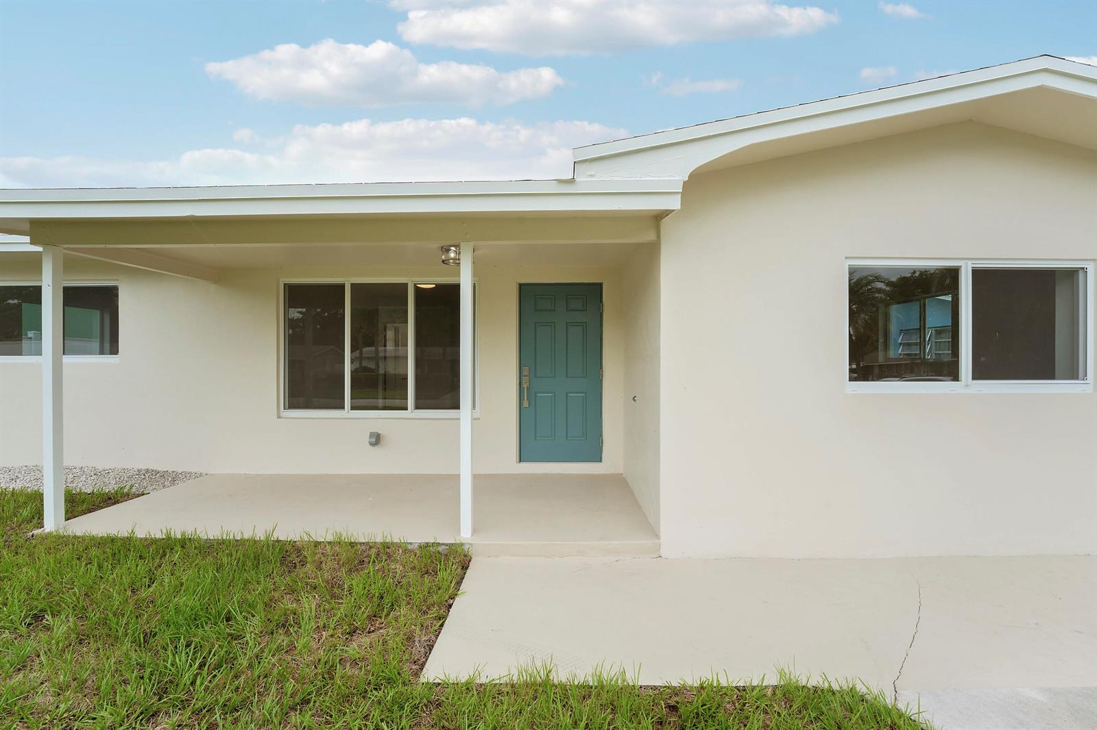 A single-story house exterior features a covered porch, a teal front door, and white walls — 4142 Kirkland Lane, Lake Worth FL 33461, LAKE WORTH, FL