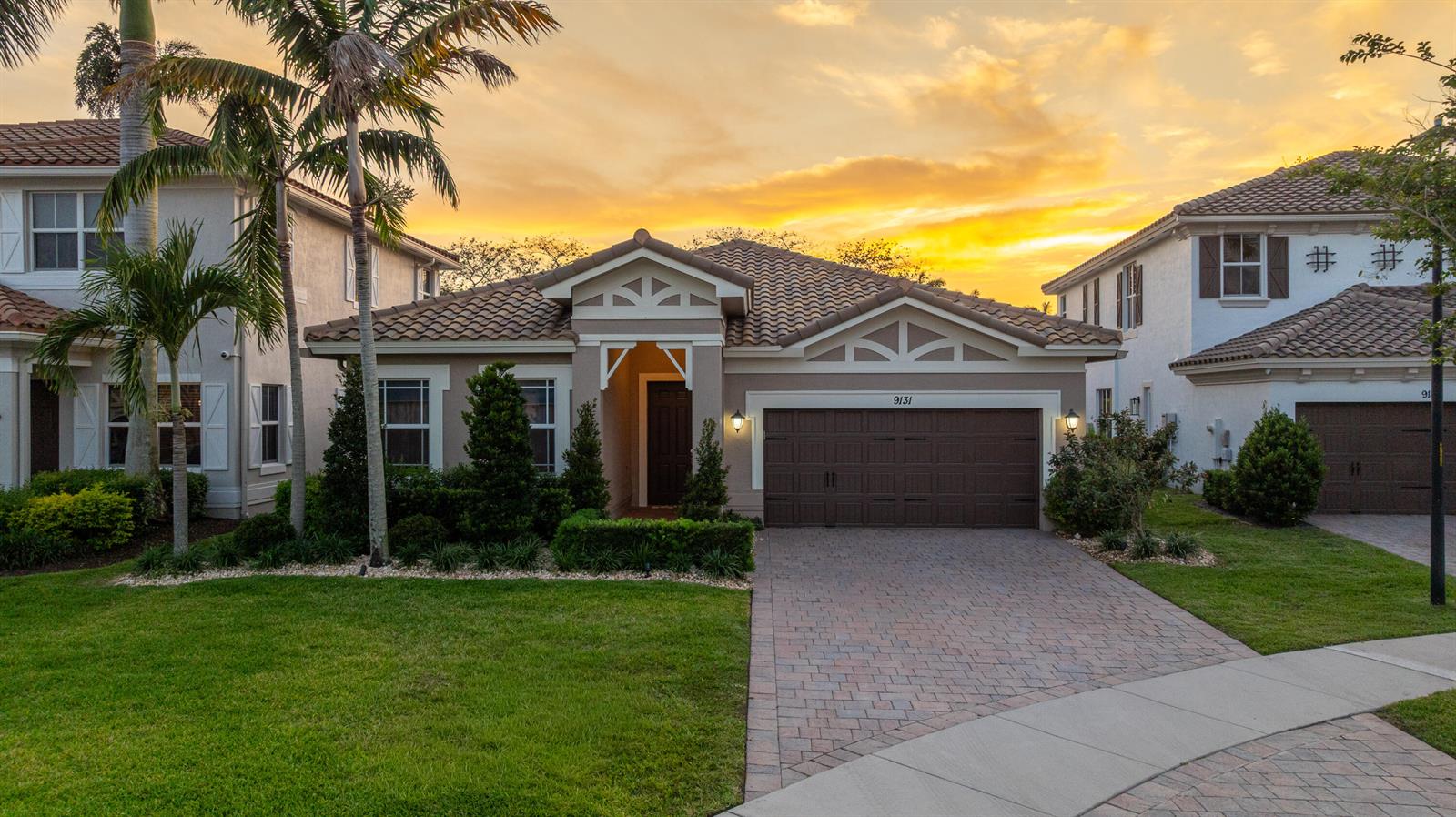 A single-story house with a brown garage, tile roof, and palm trees at sunset — 9131 Cattail Run, Parkland FL 33076, PARKLAND, FL