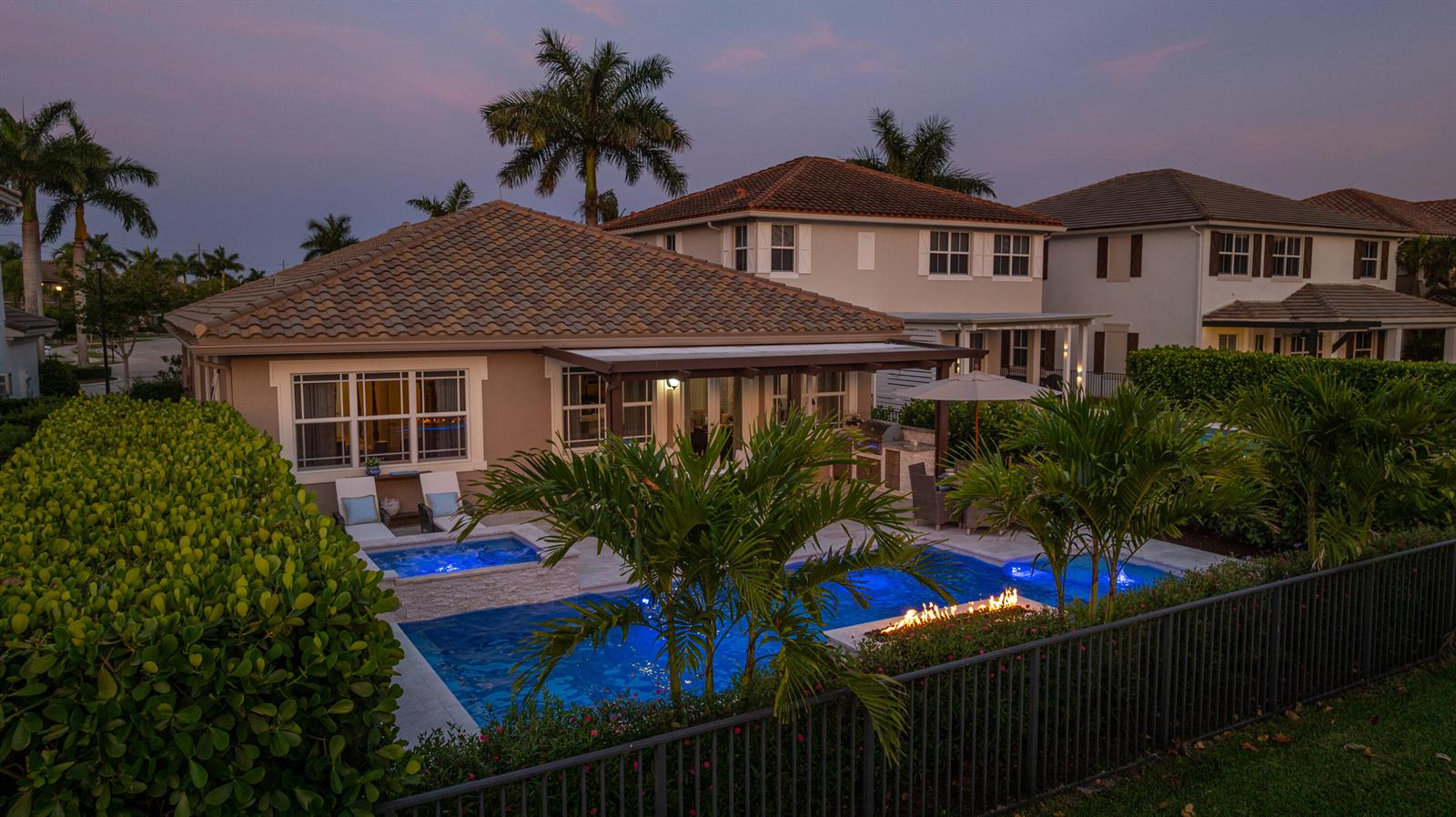 A backyard pool and hot tub with a fire feature sit behind a suburban house — 9131 Cattail Run, Parkland FL 33076, PARKLAND, FL