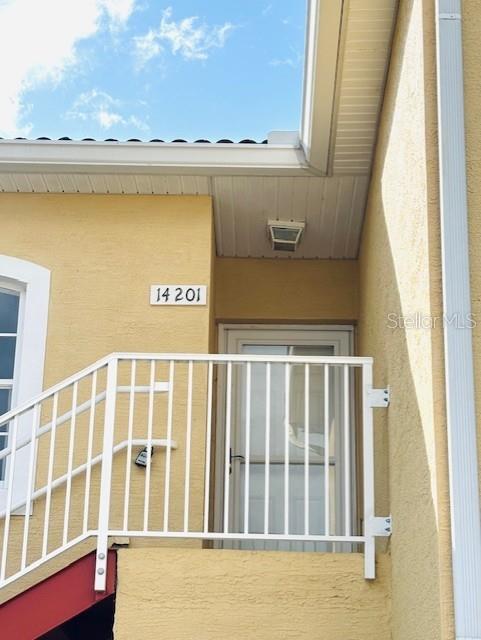 An exterior view shows a yellow building entrance with a white railing and a door — 14201 INDIAN CREEK DRIVE UNIT 14201, KISSIMMEE, FL