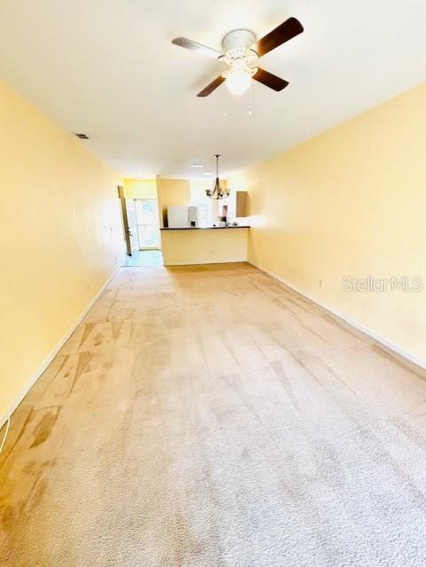 A living room with beige carpet and yellow walls leads to an open kitchen area — 14201 INDIAN CREEK DRIVE UNIT 14201, KISSIMMEE, FL
