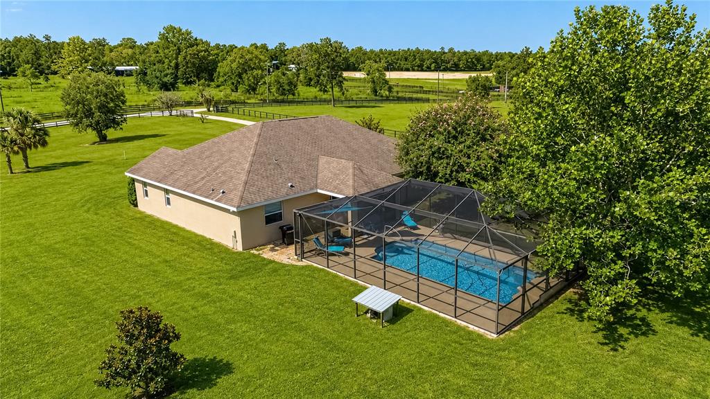 An aerial view shows a single-story house with a screened-in pool on a large lawn — 16051 SW 30TH LANE, OCALA, FL