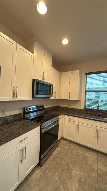 A kitchen with white cabinets, granite countertops, stainless steel appliances, and tile flooring — 14051 HELSBY STREET, ORLANDO, FL