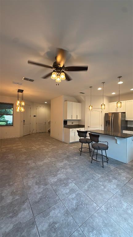 A kitchen with a granite island, bar stools, and tile flooring opens to a living area — 14051 HELSBY STREET, ORLANDO, FL