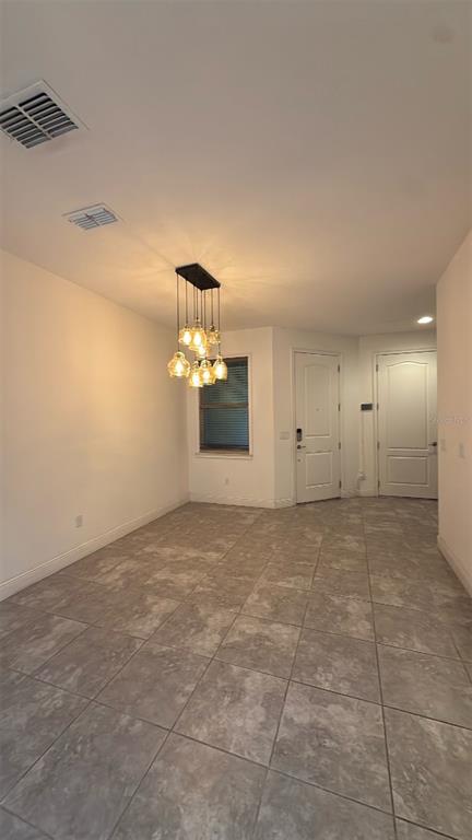 A dining area features tile flooring, a modern multi-light chandelier, and two white interior doors — 14051 HELSBY STREET, ORLANDO, FL