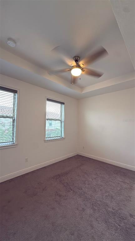 An empty bedroom features a tray ceiling with a fan, two windows, and carpeted flooring — 14051 HELSBY STREET, ORLANDO, FL
