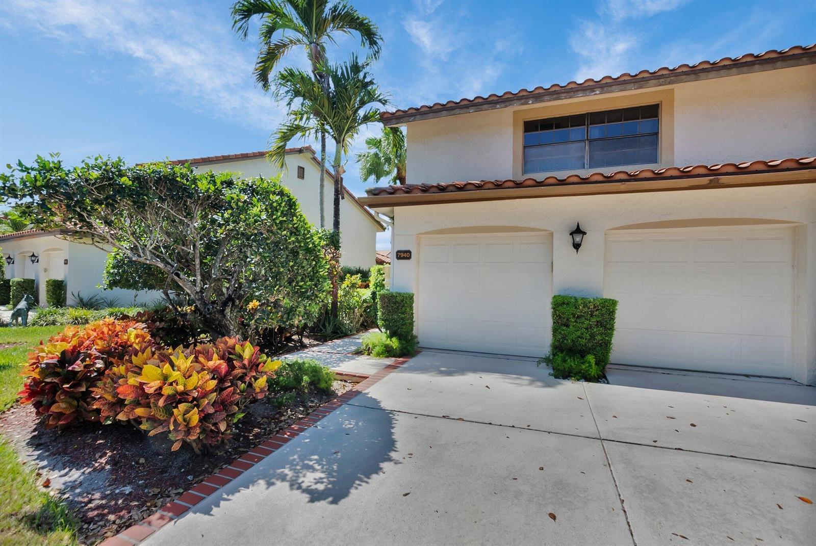 A two-story house exterior features a two-car garage, a concrete driveway, and tropical landscaping — 7940 La Mirada Drive, Boca Raton FL 33433, BOCA RATON, FL