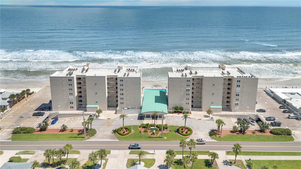 An aerial view shows two beige oceanfront condominium buildings with a central pool area — 4505 S ATLANTIC AVENUE UNIT 305, PONCE INLET, FL
