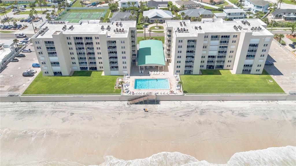 An aerial view of a multi-story beachfront condominium complex with a pool and green lawn — 4505 S ATLANTIC AVENUE UNIT 305, PONCE INLET, FL