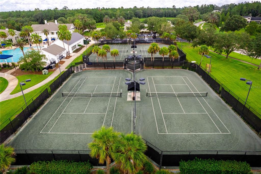 An aerial view shows two sets of fenced tennis courts next to a swimming pool — 5995 CREEK RIDGE ROAD, BROOKSVILLE, FL
