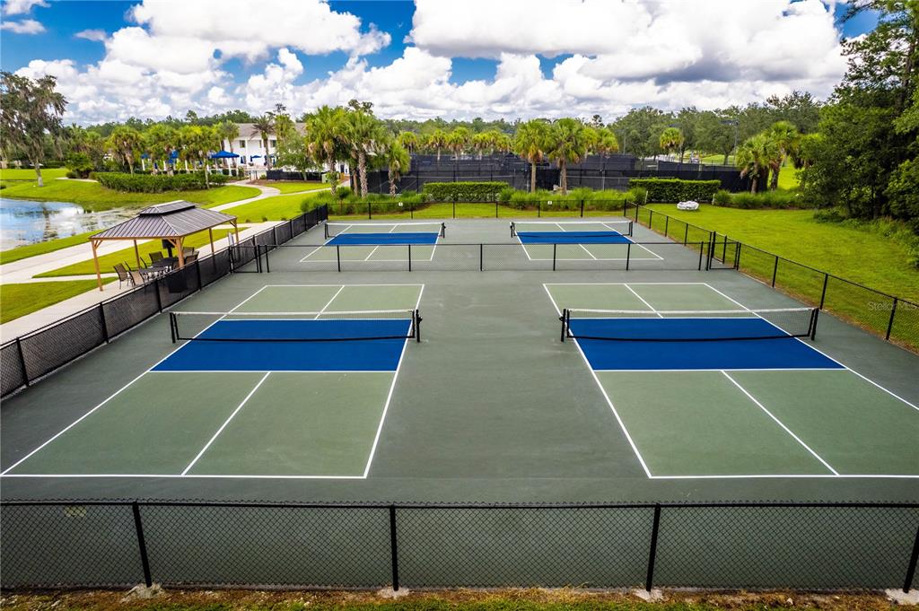 An elevated view shows four pickleball courts with blue surfaces and green surrounding areas — 5995 CREEK RIDGE ROAD, BROOKSVILLE, FL