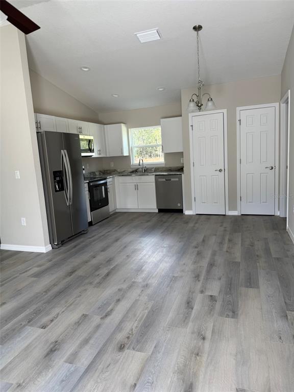 A kitchen features white cabinets, stainless steel appliances, and light gray wood-look flooring — 9539 N TRAVIS DRIVE UNIT B, CITRUS SPRINGS, FL