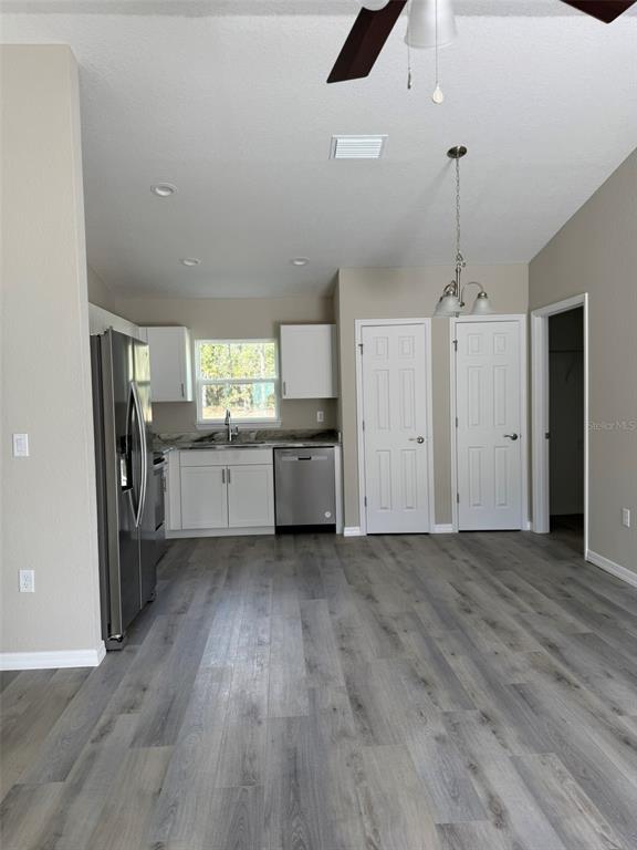 A kitchen with stainless steel appliances, white cabinets, and gray wood-look flooring — 9539 N TRAVIS DRIVE UNIT B, CITRUS SPRINGS, FL