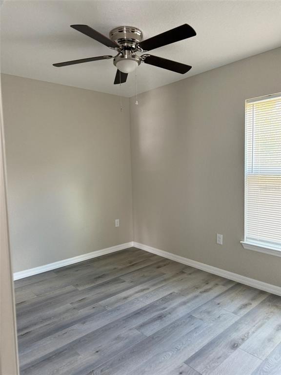 An empty bedroom features light gray walls, wood-look flooring, and a ceiling fan — 9539 N TRAVIS DRIVE UNIT B, CITRUS SPRINGS, FL