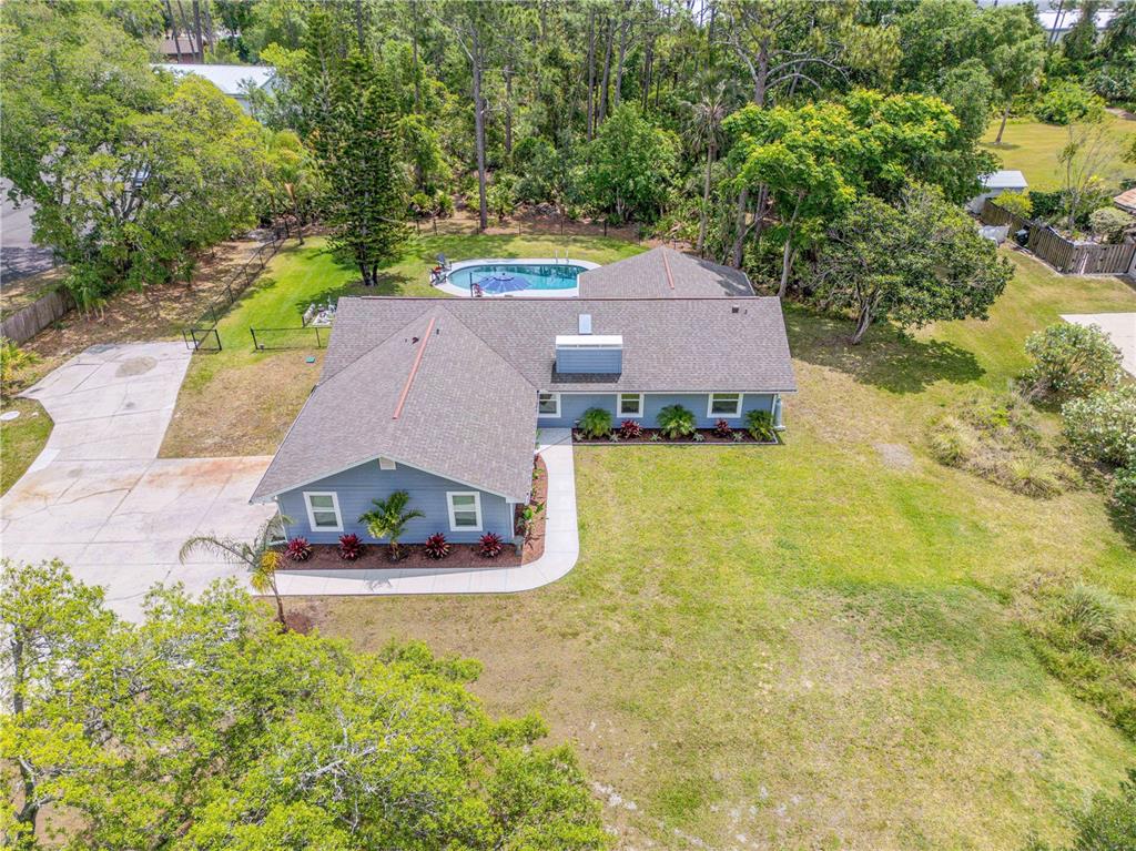An aerial view of a blue single-story house with a pool and large backyard — 106 PINE TREE DRIVE, ORMOND BEACH, FL