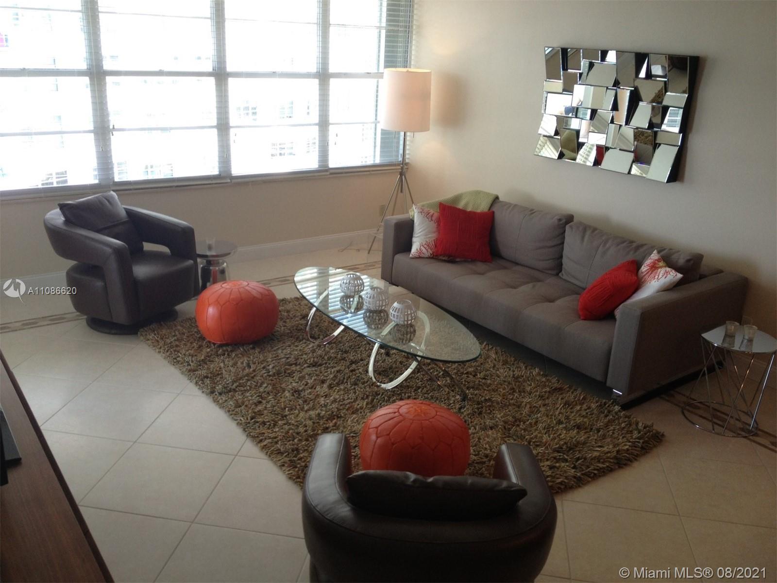 A living room features a grey sofa, two leather armchairs, orange poufs, and a glass table — 5151 COLLINS AV # 1030, Miami Beach FL 33140, MIAMI BEACH, FL