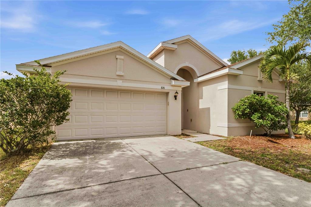 A single-story beige house with a two-car garage and a concrete driveway — 820 PARKER DEN DRIVE, RUSKIN, FL