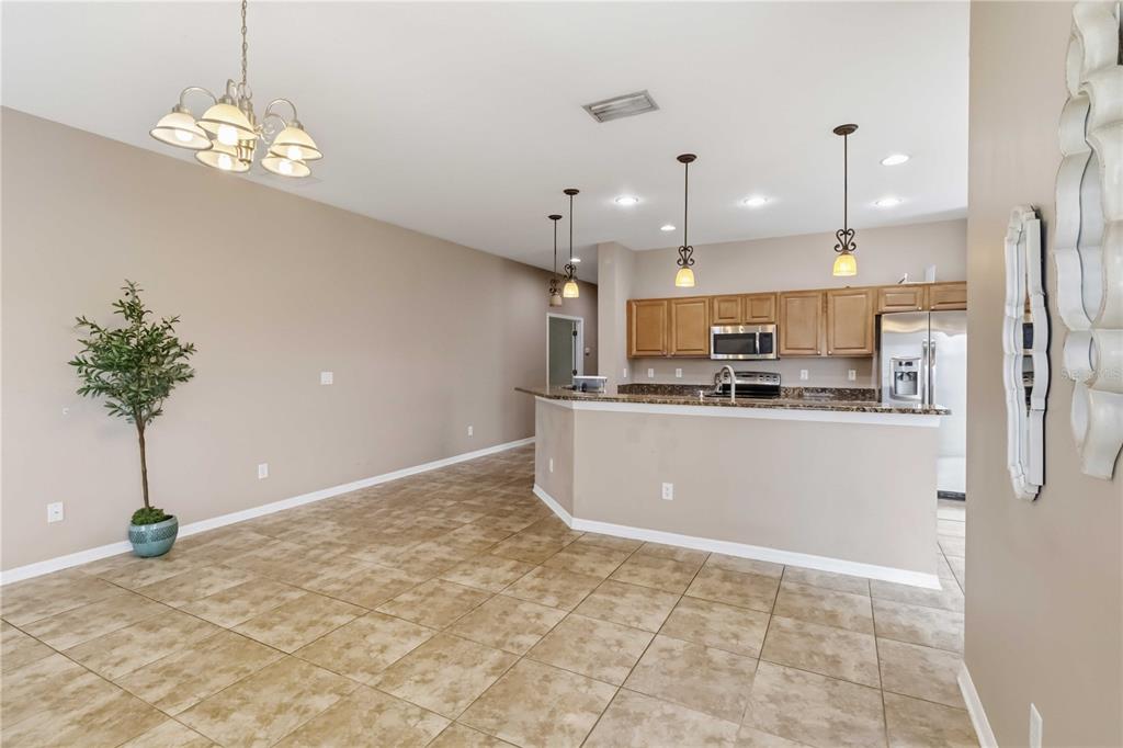 An open-concept kitchen with wood cabinets and a breakfast bar overlooks a tiled dining area — 820 PARKER DEN DRIVE, RUSKIN, FL