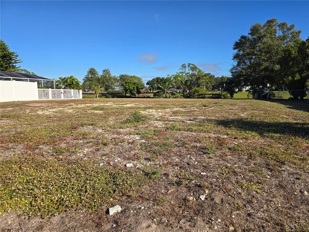 A flat, grassy vacant lot with scattered patches of dirt and surrounding trees — 5722 ESPANOLA AVENUE, NORTH PORT, FL