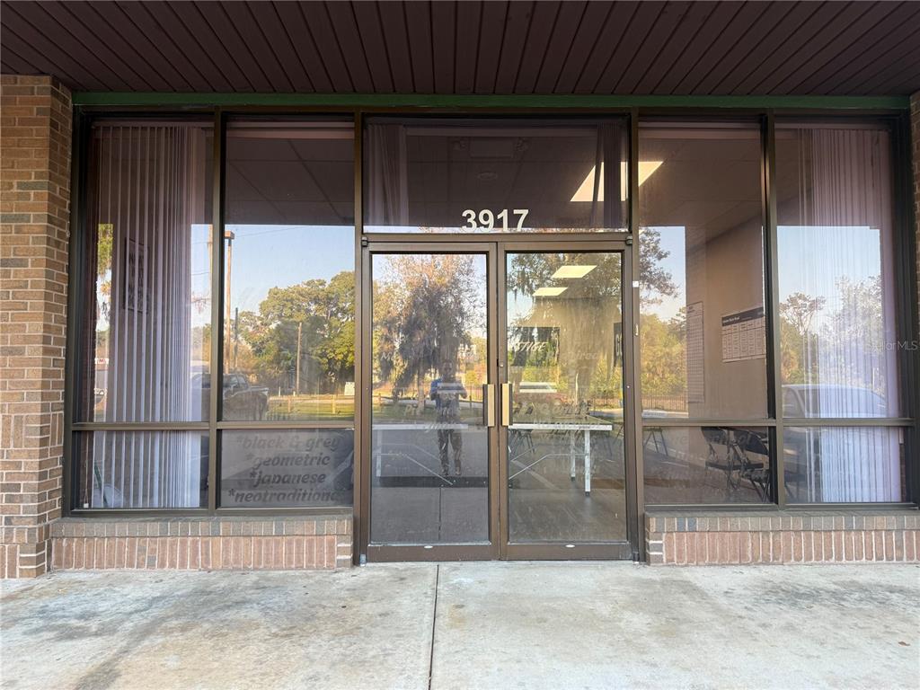 The exterior of a commercial storefront features a glass double door and large display windows — 3917 SE LAKE WEIR AVENUE, OCALA, FL