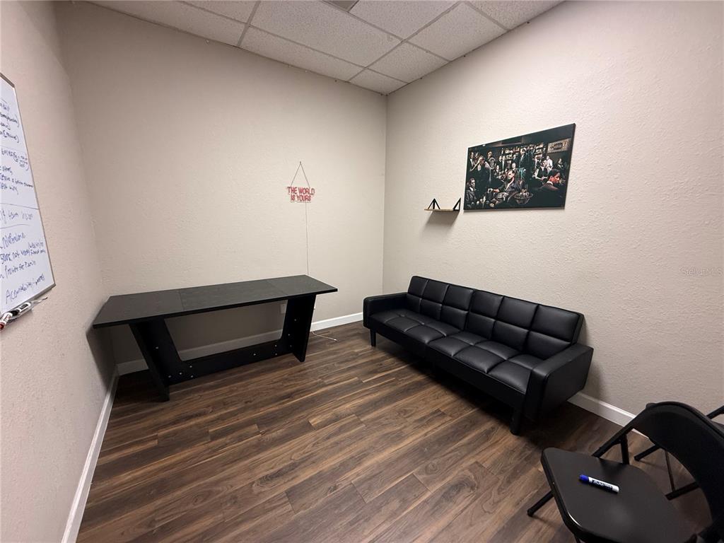 An office room features wood-look flooring, a black desk, a black sofa, and wall art — 3917 SE LAKE WEIR AVENUE, OCALA, FL