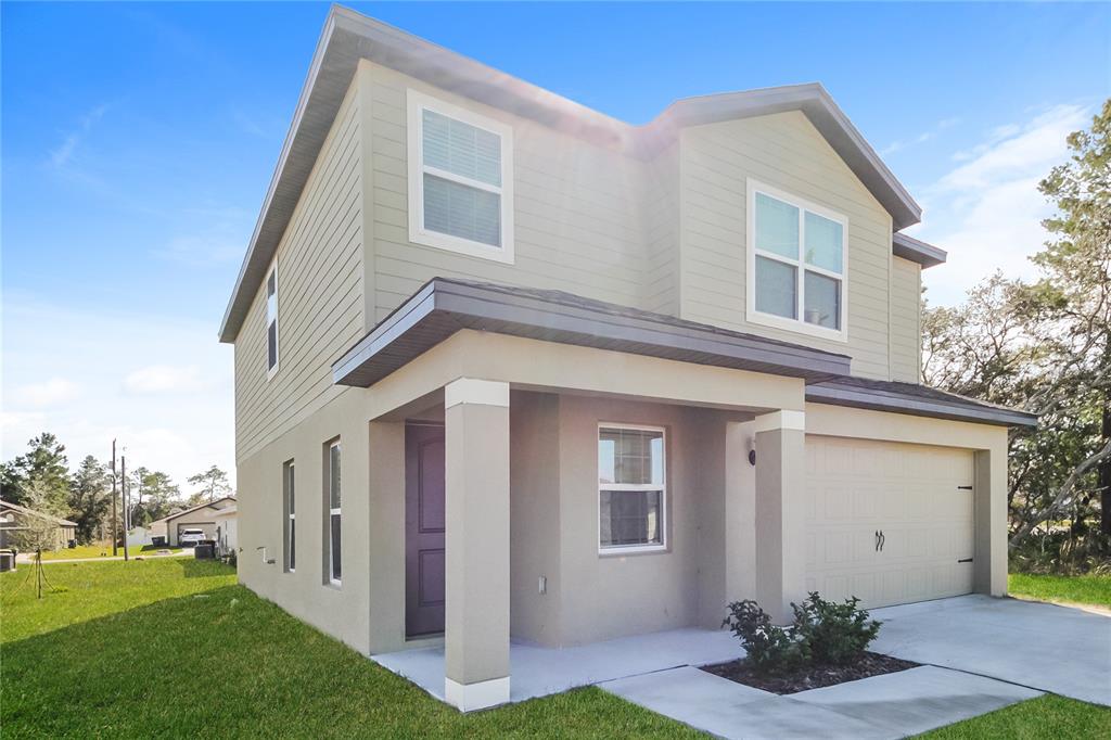 A two-story house with tan siding, a front porch, and an attached garage — 204 FIG COURT, KISSIMMEE, FL