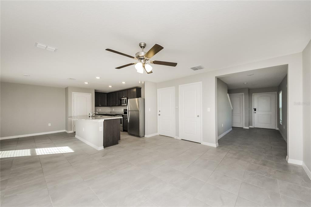 An open-concept kitchen and living area features gray tile flooring, dark cabinetry, and a ceiling fan — 204 FIG COURT, KISSIMMEE, FL