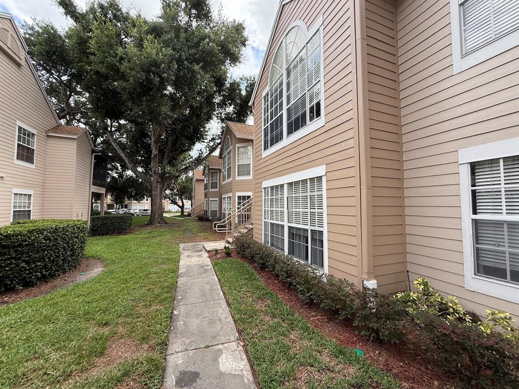 A sidewalk leads between beige apartment buildings with large windows and surrounding green landscaping — 696 YOUNGSTOWN PARKWAY UNIT 315, ALTAMONTE SPRINGS, FL