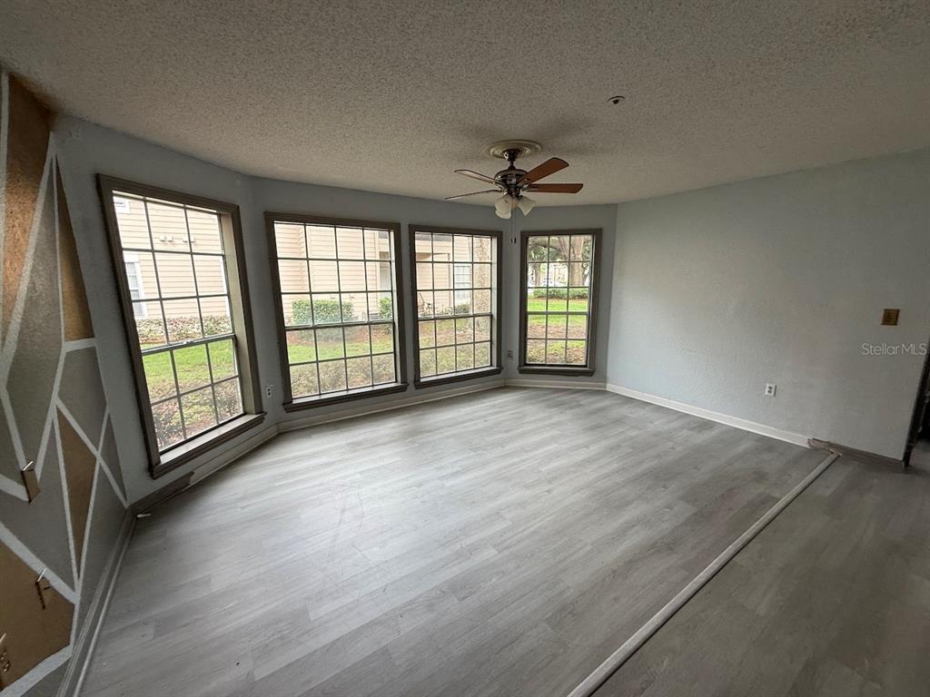 An empty room with light gray wood-look flooring, a ceiling fan, and large bay windows — 696 YOUNGSTOWN PARKWAY UNIT 315, ALTAMONTE SPRINGS, FL