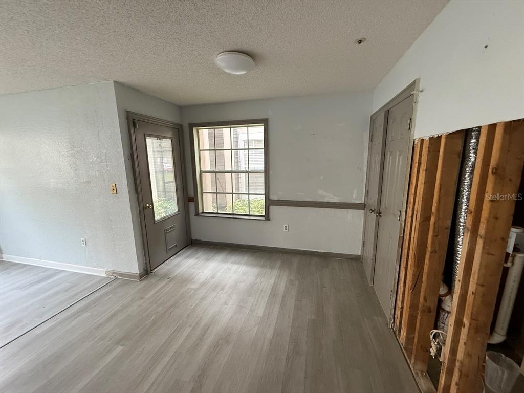A room with light wood-look flooring, a window, a door, and an unfinished wall section — 696 YOUNGSTOWN PARKWAY UNIT 315, ALTAMONTE SPRINGS, FL