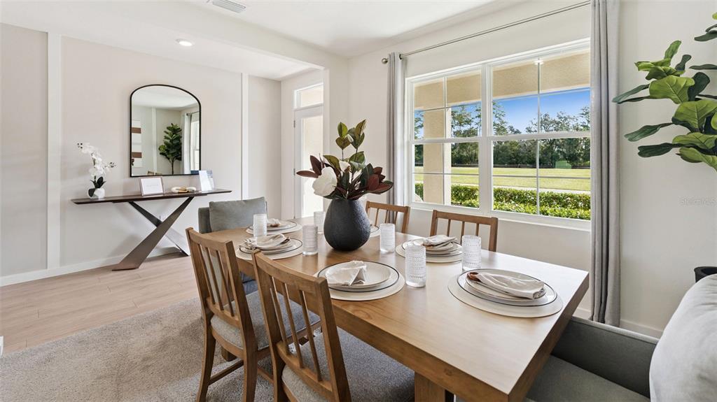 A dining room features a wooden table, chairs, a console table, and large windows — 1519 BEECHMONT DRIVE, KISSIMMEE, FL