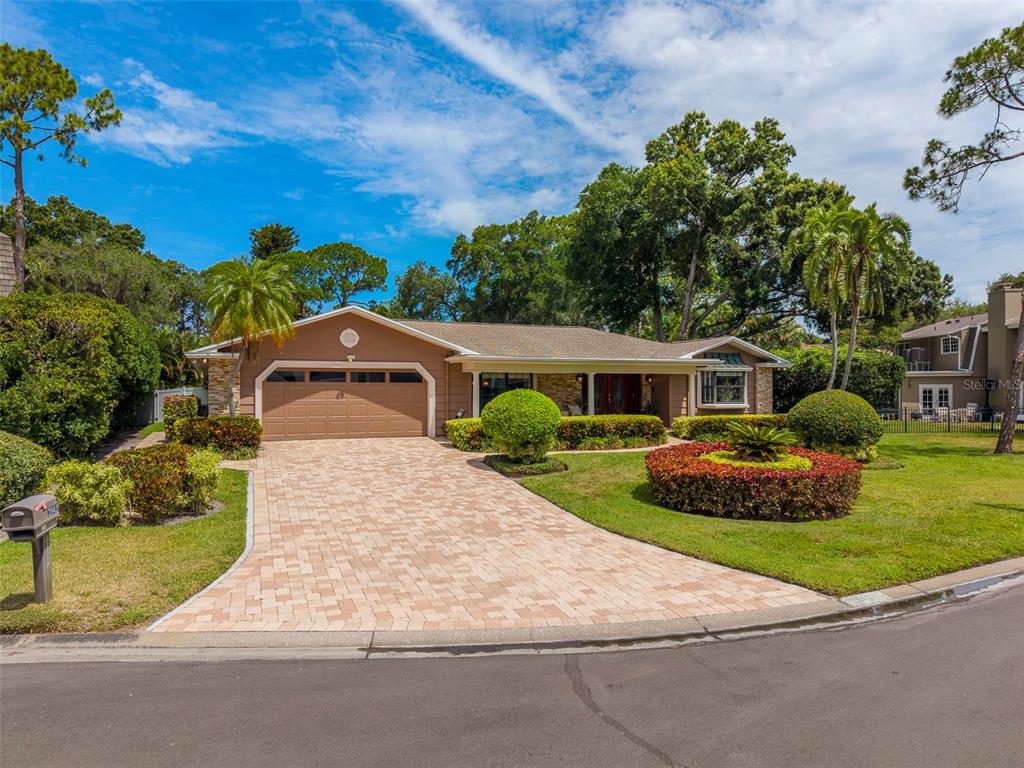 A single-story house with a tan exterior, a paved driveway, and manicured landscaping — 2943 WHISPER LANE N, CLEARWATER, FL