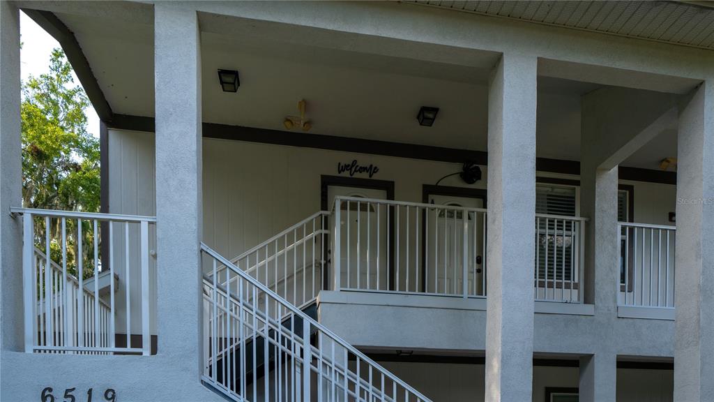 An exterior view shows a multi-story building with white railings, stairs, and two entrance doors — 6519 W NEWBERRY RD UNIT A5, GAINESVILLE, FL